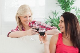 15590544-women-sitting-on-the-couch-drinking-wine-together-at-home